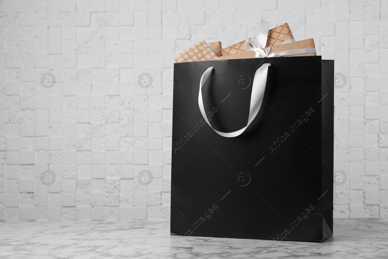 Photo of Paper shopping bag with handles full of gift boxes on table. Mock up for design