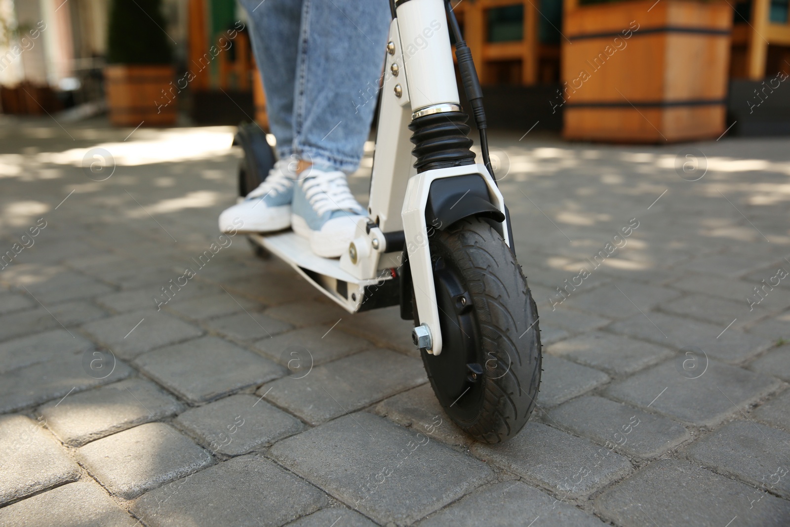 Photo of Woman riding electric kick scooter outdoors, closeup