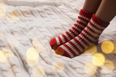 Image of Woman in warm socks on knitted blanket, closeup. Space for text