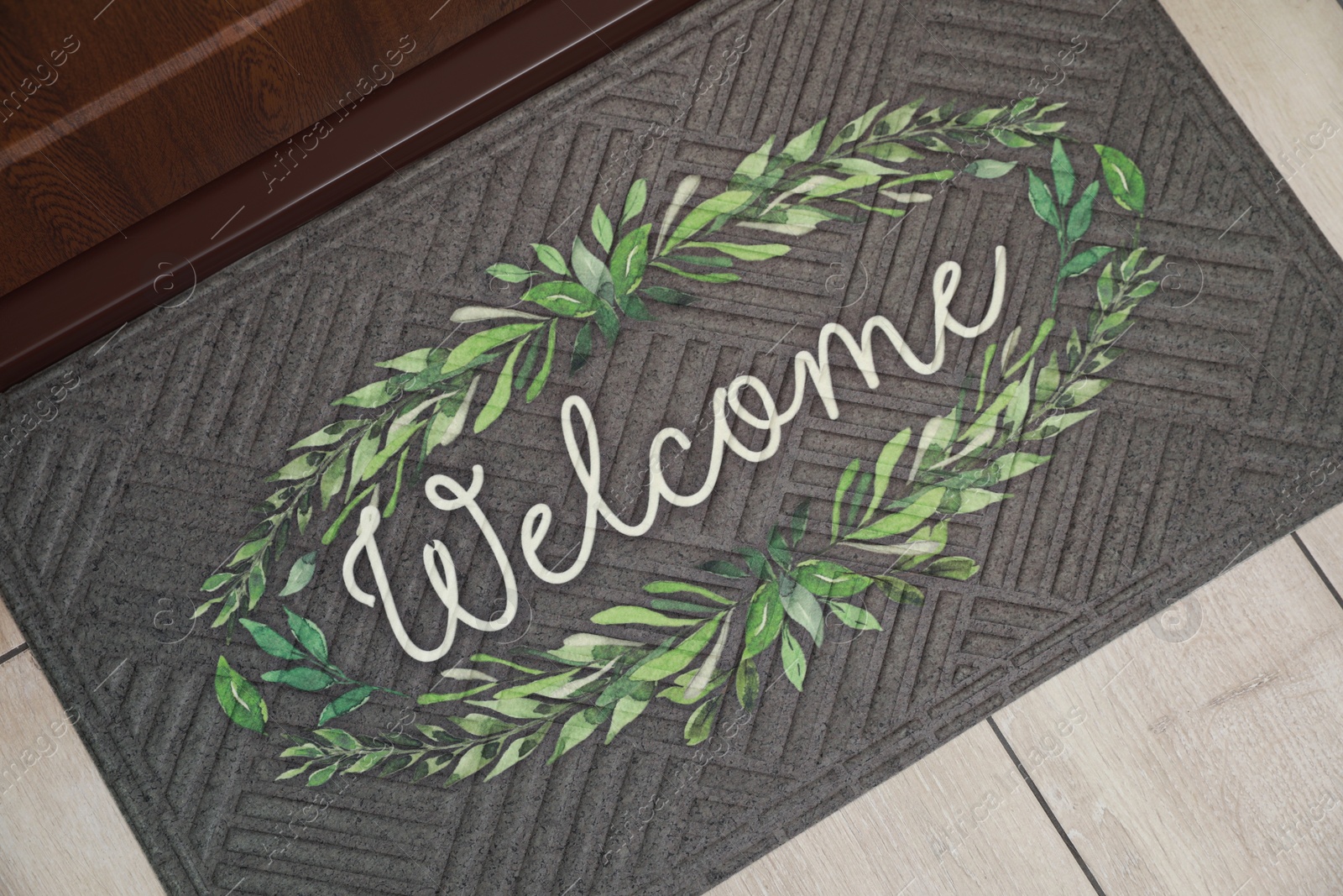 Photo of Beautiful doormat with word Welcome on floor near entrance, top view