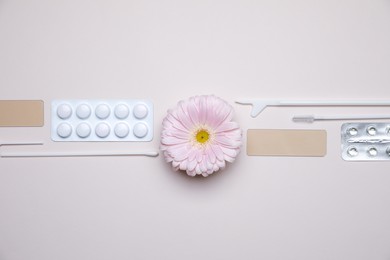 Sterile gynecological tools, pills and gerbera flower on beige background, flat lay