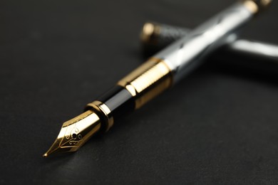 Photo of Beautiful fountain pen with ornate nib on black table, closeup