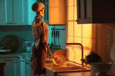 Photo of Human skeleton washing dishes in kitchen sink at night