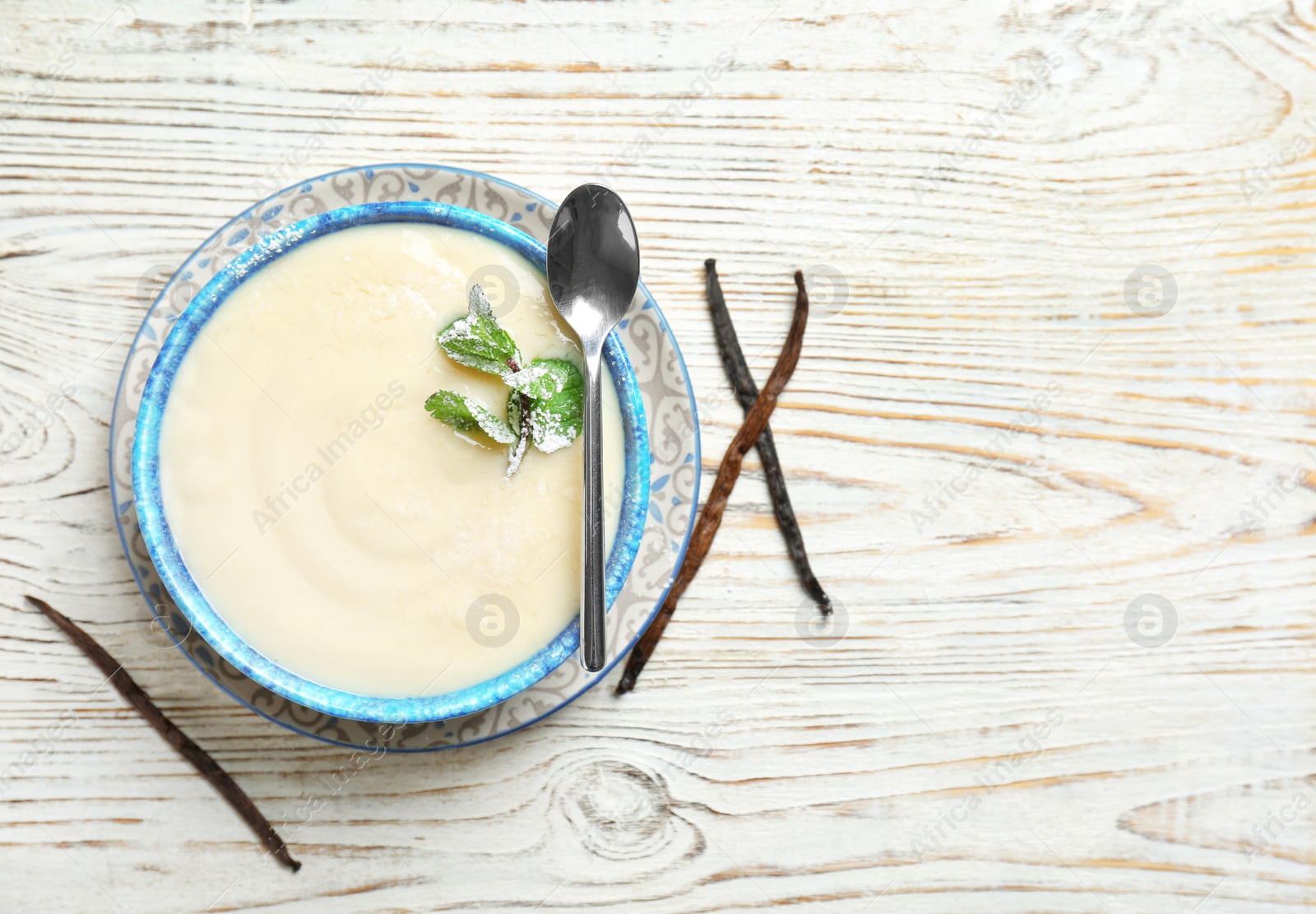 Photo of Vanilla pudding, sticks and fresh mint on wooden background