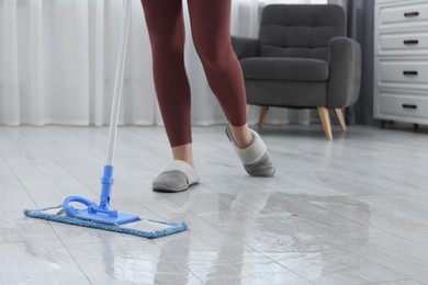 Photo of Woman cleaning floor with mop indoors, closeup