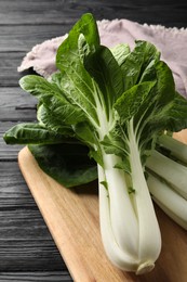 Photo of Fresh green pak choy cabbages on black wooden table, closeup