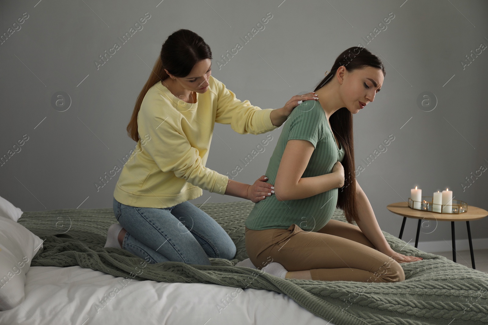 Photo of Doula massaging pregnant woman in bedroom. Preparation for child birth