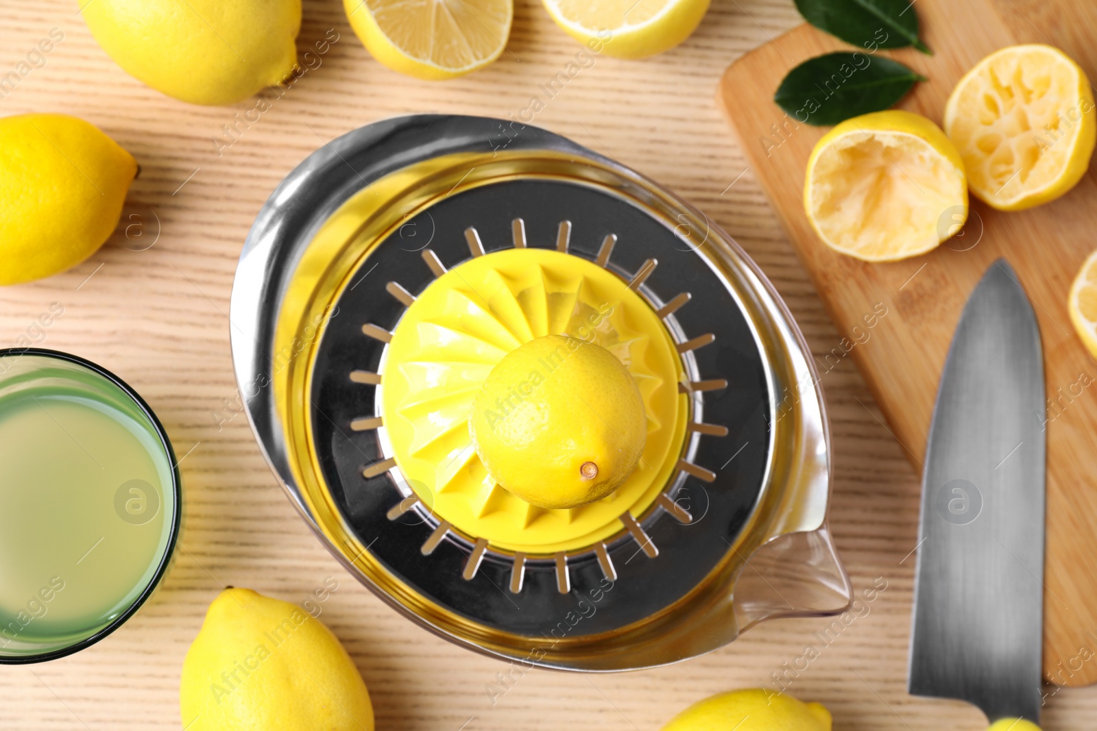 Photo of Flat lay composition with fresh lemons and juicer on wooden table