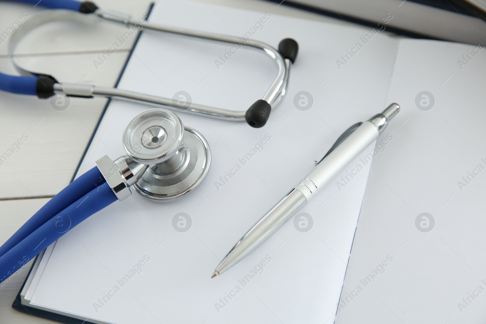 Photo of One new medical stethoscope on white wooden table, closeup