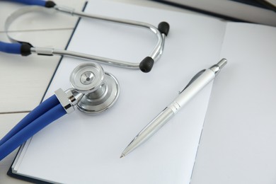 Photo of One new medical stethoscope on white wooden table, closeup