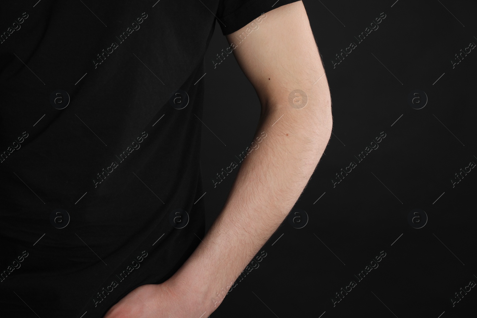 Photo of Man with space for tattoo on his arm against black background, closeup