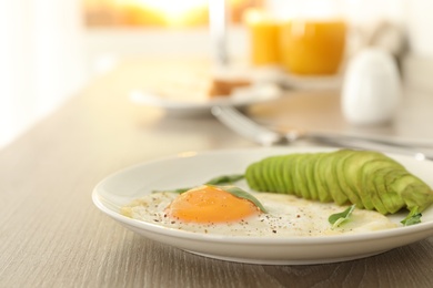 Photo of Tasty breakfast with fried egg and avocado on wooden table, closeup