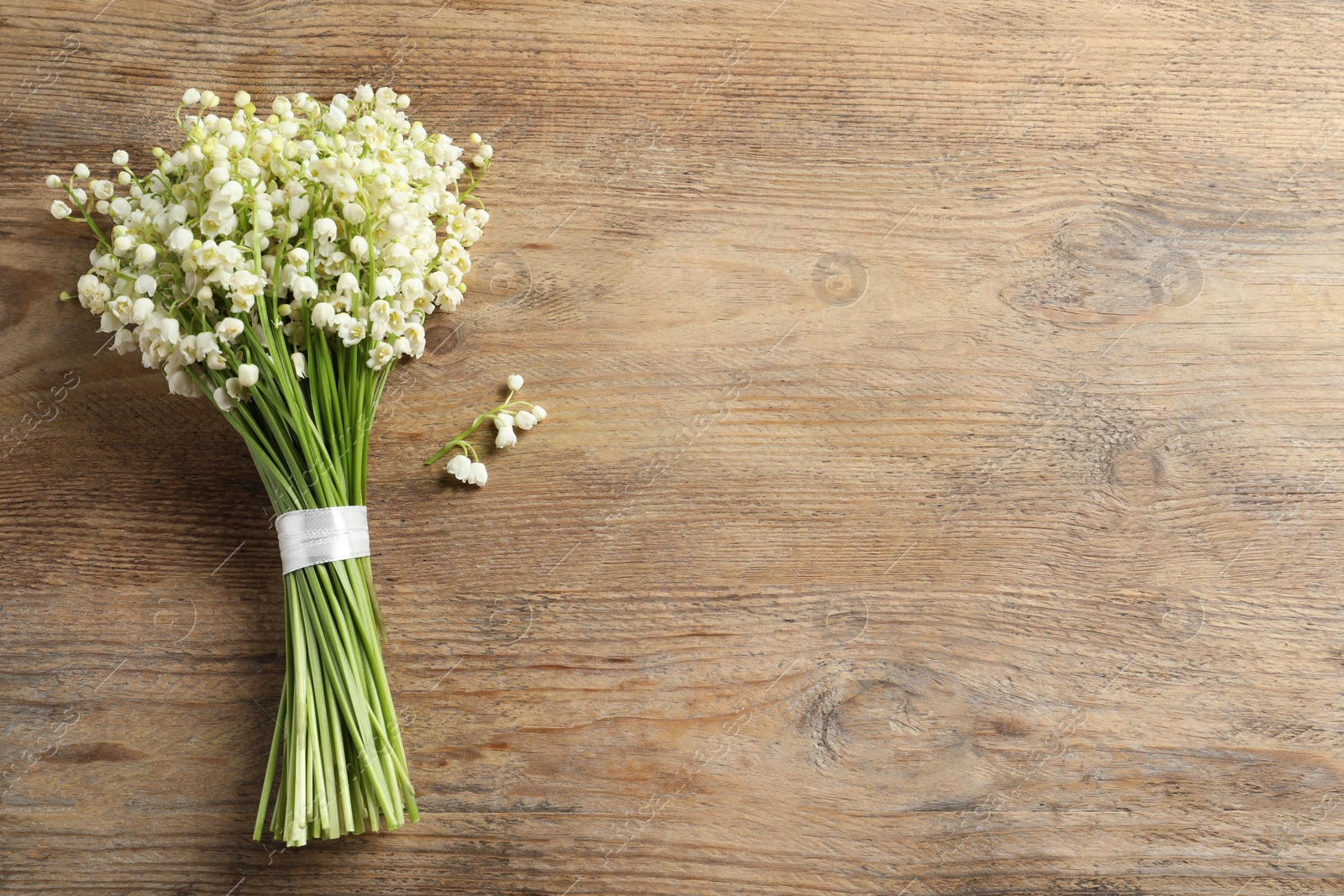 Photo of Beautiful lily of the valley bouquet on wooden table, top view. Space for text