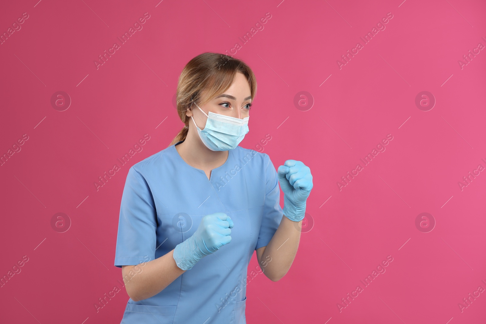 Photo of Doctor with protective mask in fighting pose on pink background, space for text. Strong immunity concept