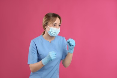 Doctor with protective mask in fighting pose on pink background, space for text. Strong immunity concept