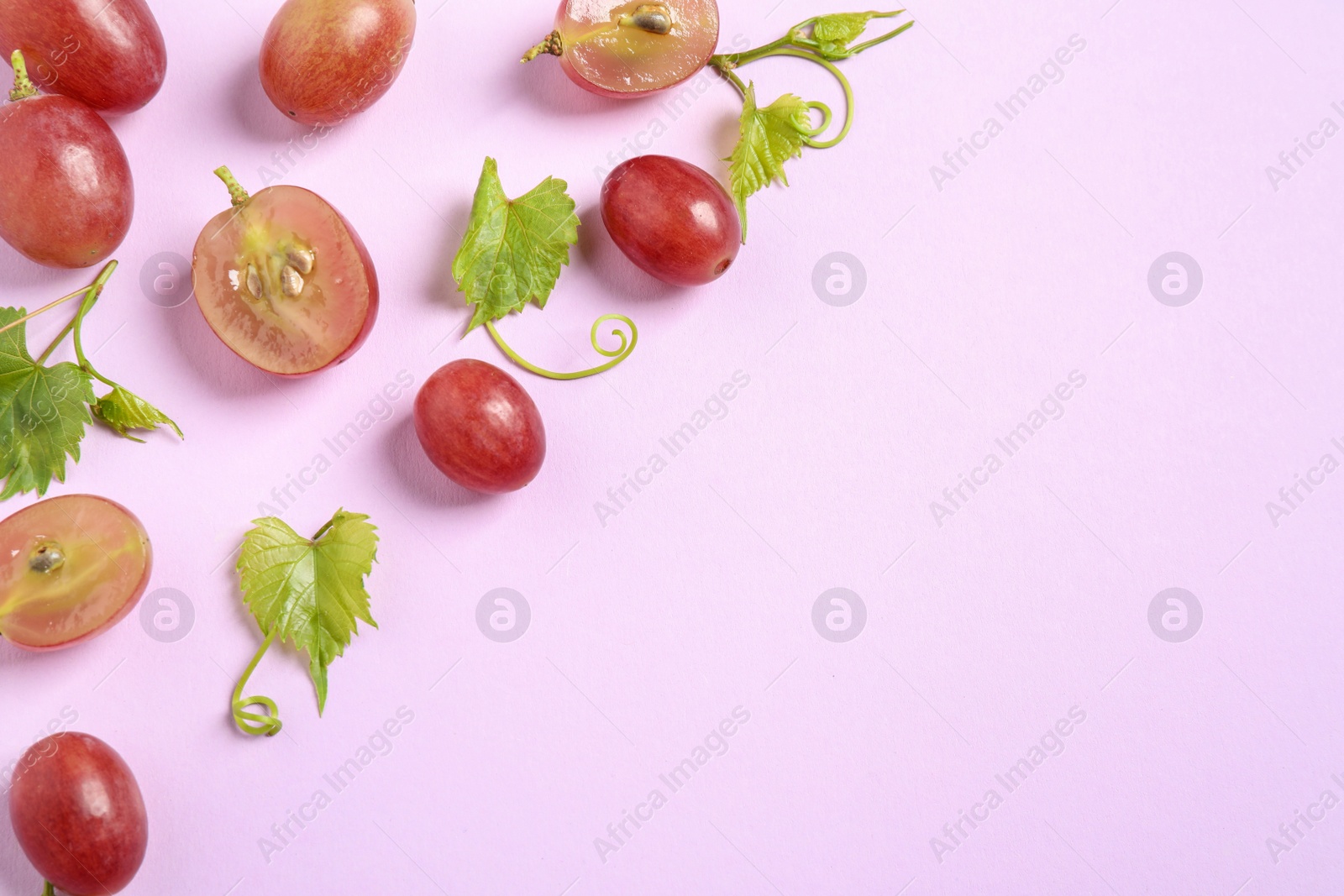 Photo of Flat lay composition with fresh ripe juicy grapes on lilac background, space for text