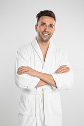 Happy young man in bathrobe on white background