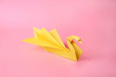 Photo of Origami art. Beautiful paper swan on pink background