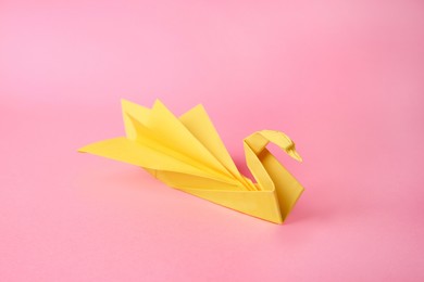 Origami art. Beautiful paper swan on pink background