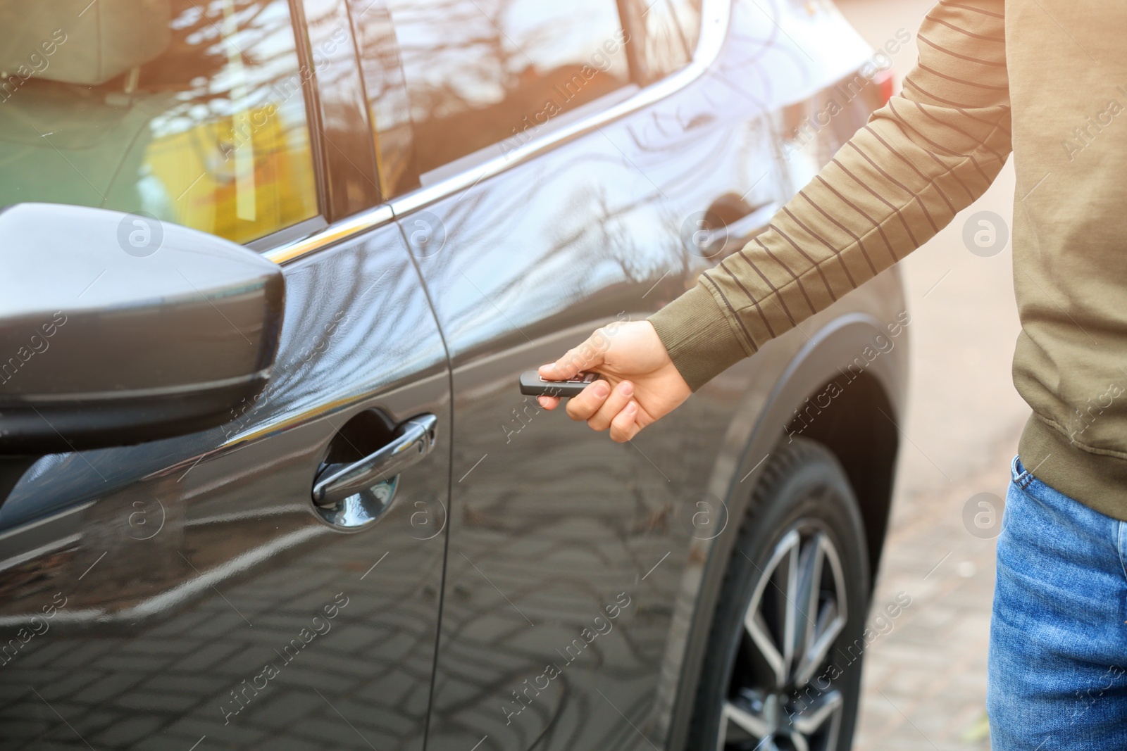 Photo of Closeup view of man opening car door with remote key