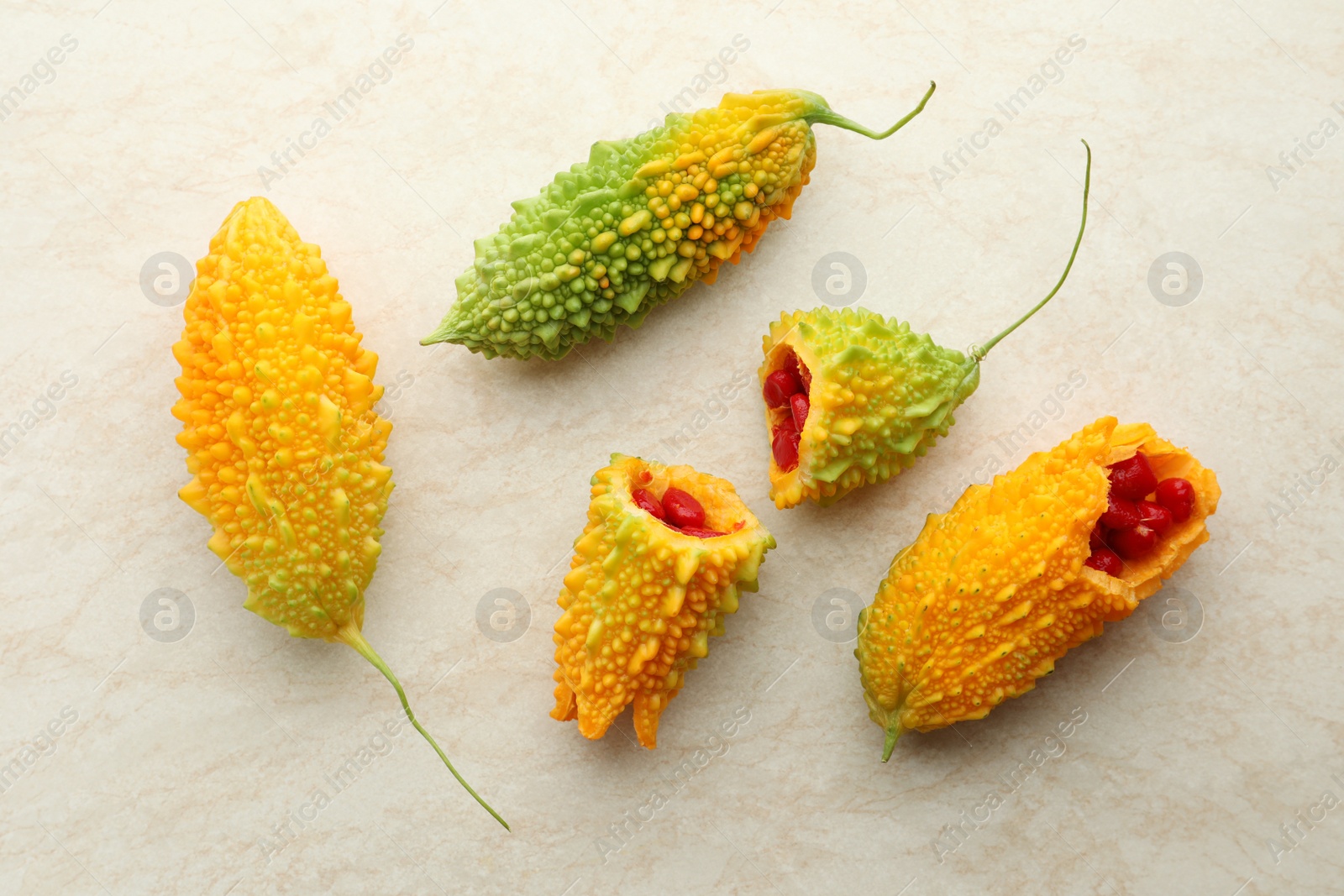 Photo of Fresh bitter melons with red seeds on light table, flat lay