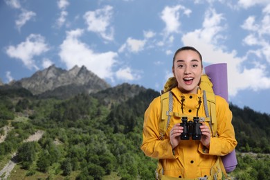 Image of Happy tourist with backpack and binoculars in mountains