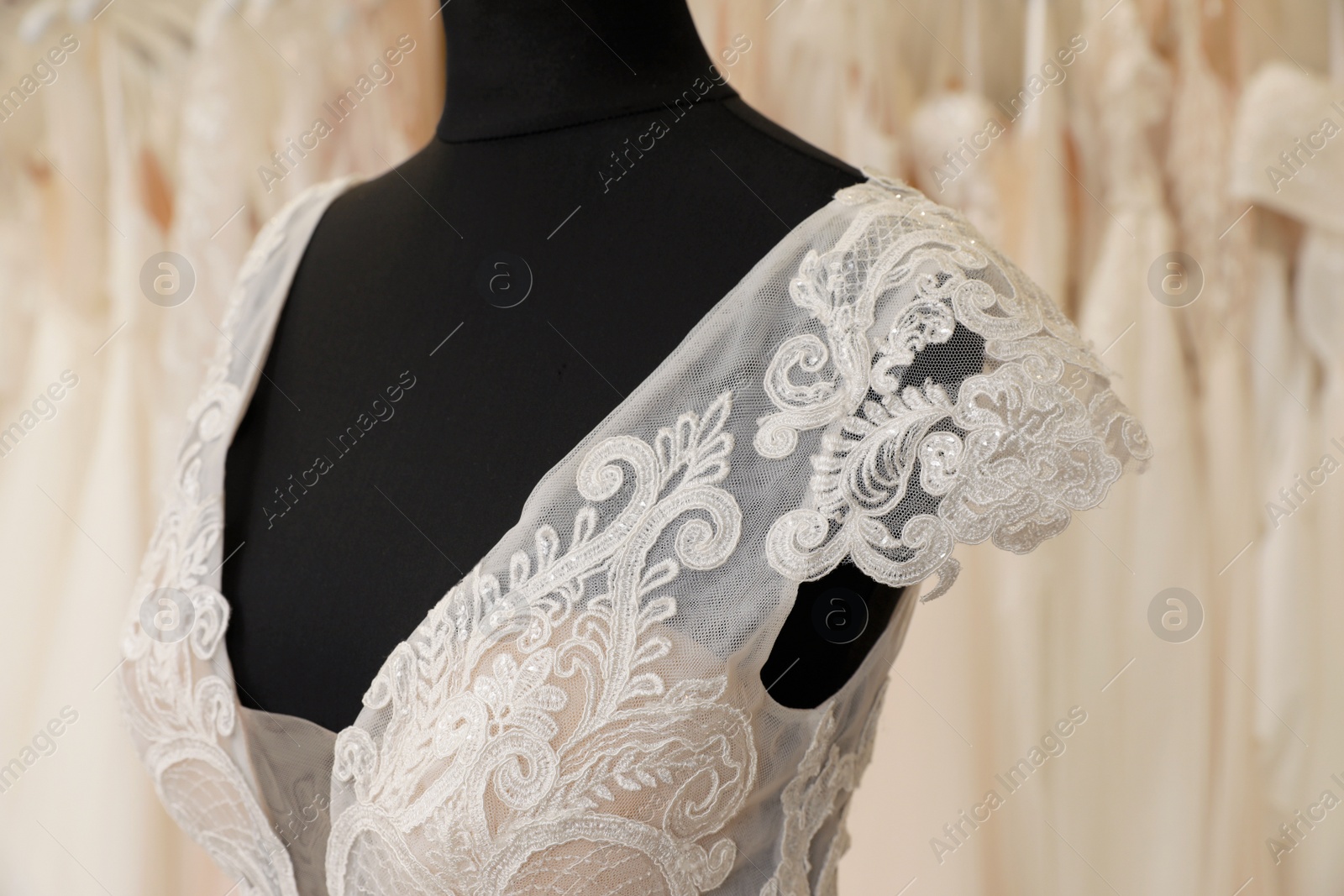 Photo of Beautiful wedding dress on mannequin in boutique, closeup