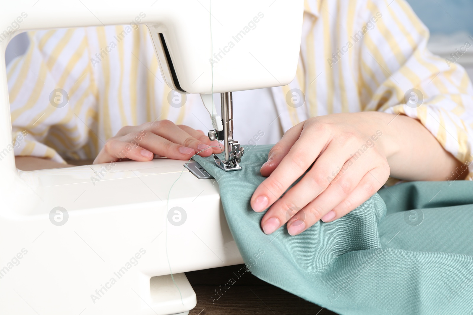 Photo of Seamstress working with sewing machine indoors, closeup