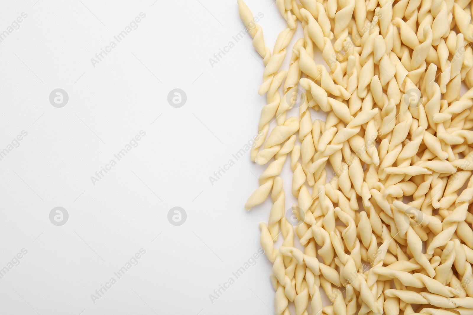 Photo of Uncooked trofie pasta on white background, flat lay. Space for text