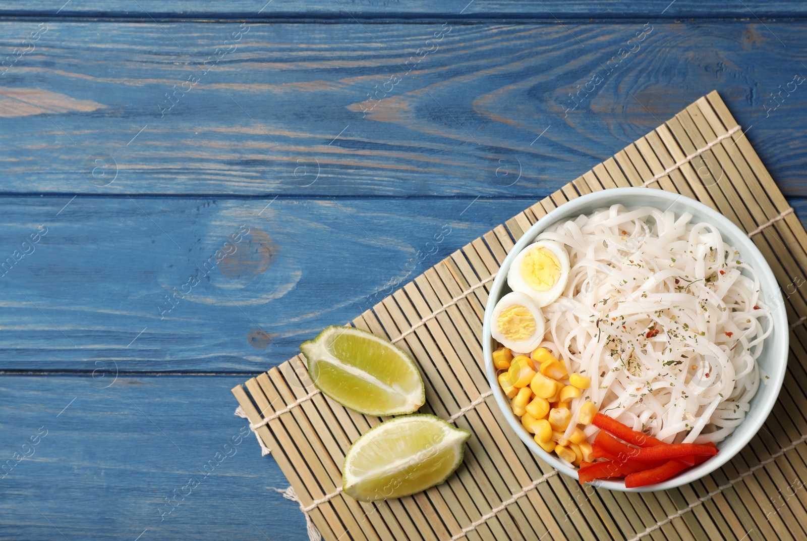 Photo of Flat lay composition with rice noodles in bowl on wooden background. Space for text