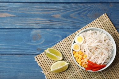 Photo of Flat lay composition with rice noodles in bowl on wooden background. Space for text