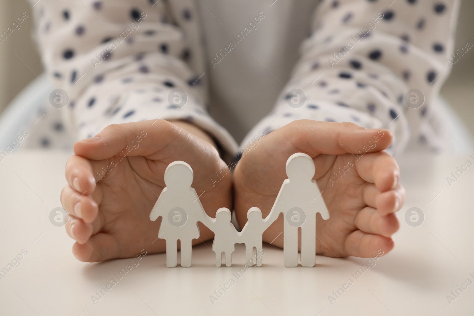 Photo of Woman with figure of family at white table, closeup