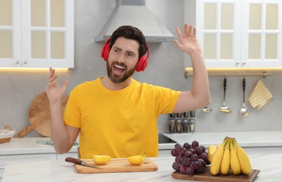 Photo of Emotional man listening music with headphones in kitchen