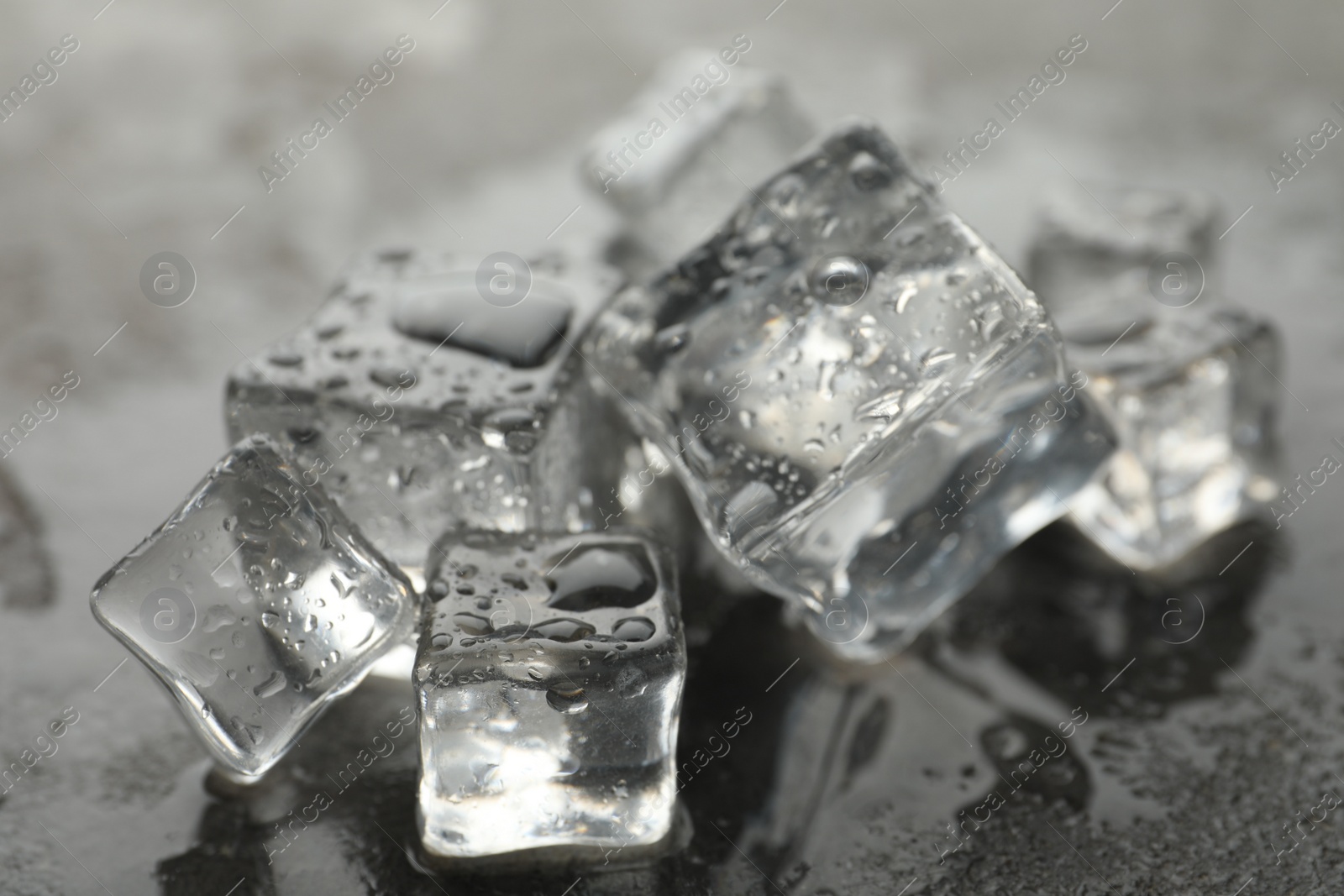 Photo of Crystal clear ice cubes with water drops on grey table, closeup