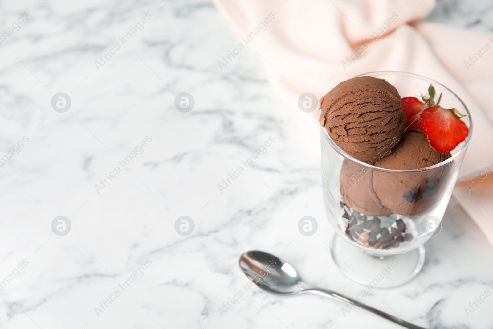 Photo of Glass bowl of chocolate ice cream with strawberry served on marble table, space for text
