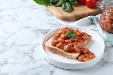 Photo of Toast with delicious canned beans on white marble table, space for text