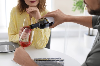 Photo of Young couple with glasses of wine at table in restaurant