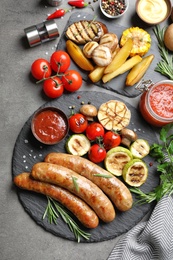 Photo of Delicious sausages and vegetables served for barbecue party on gray background, top view