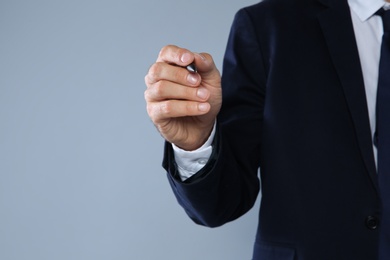 Businessman writing against grey background, closeup view of hand with space for text