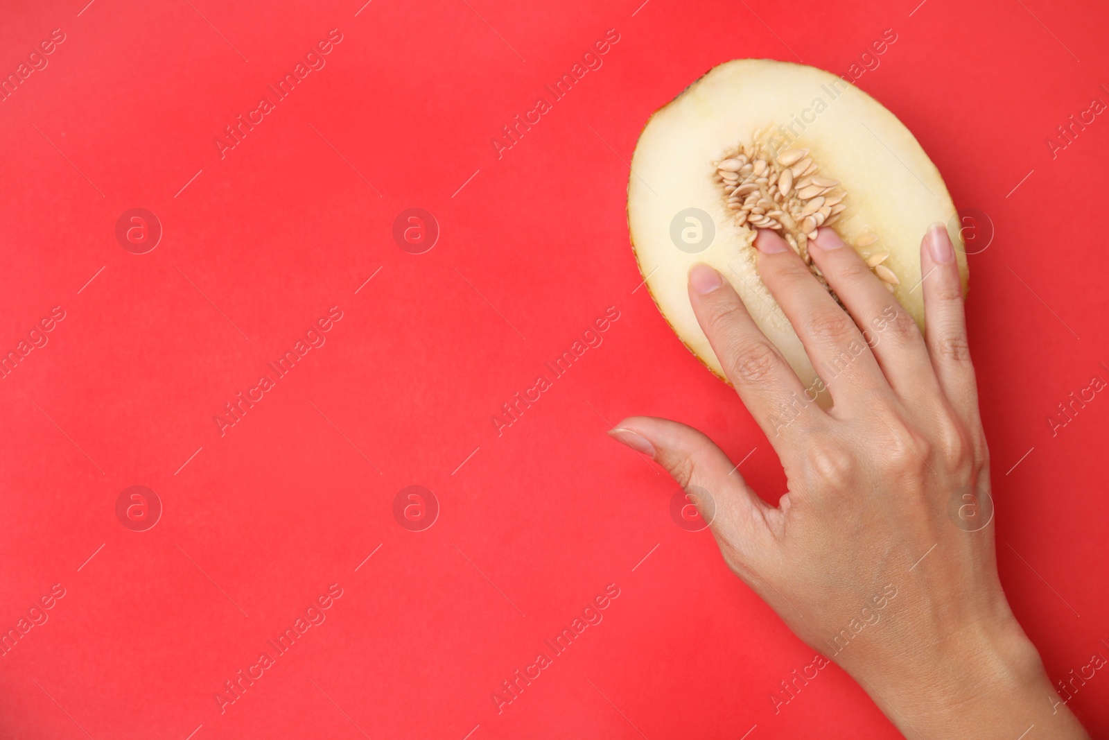 Photo of Young woman touching half of melon on red background, top view with space for text. Sex concept