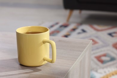 Yellow mug of tea on wooden table indoors, space for text