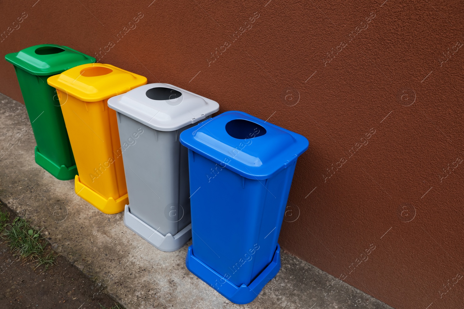 Photo of Many color recycling bins near brown wall outdoors, space for text