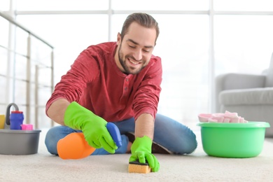 Young man cleaning carpet at home