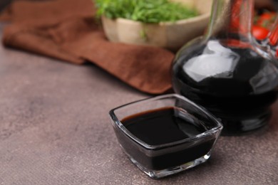 Photo of Organic balsamic vinegar on grey table, closeup. Space for text