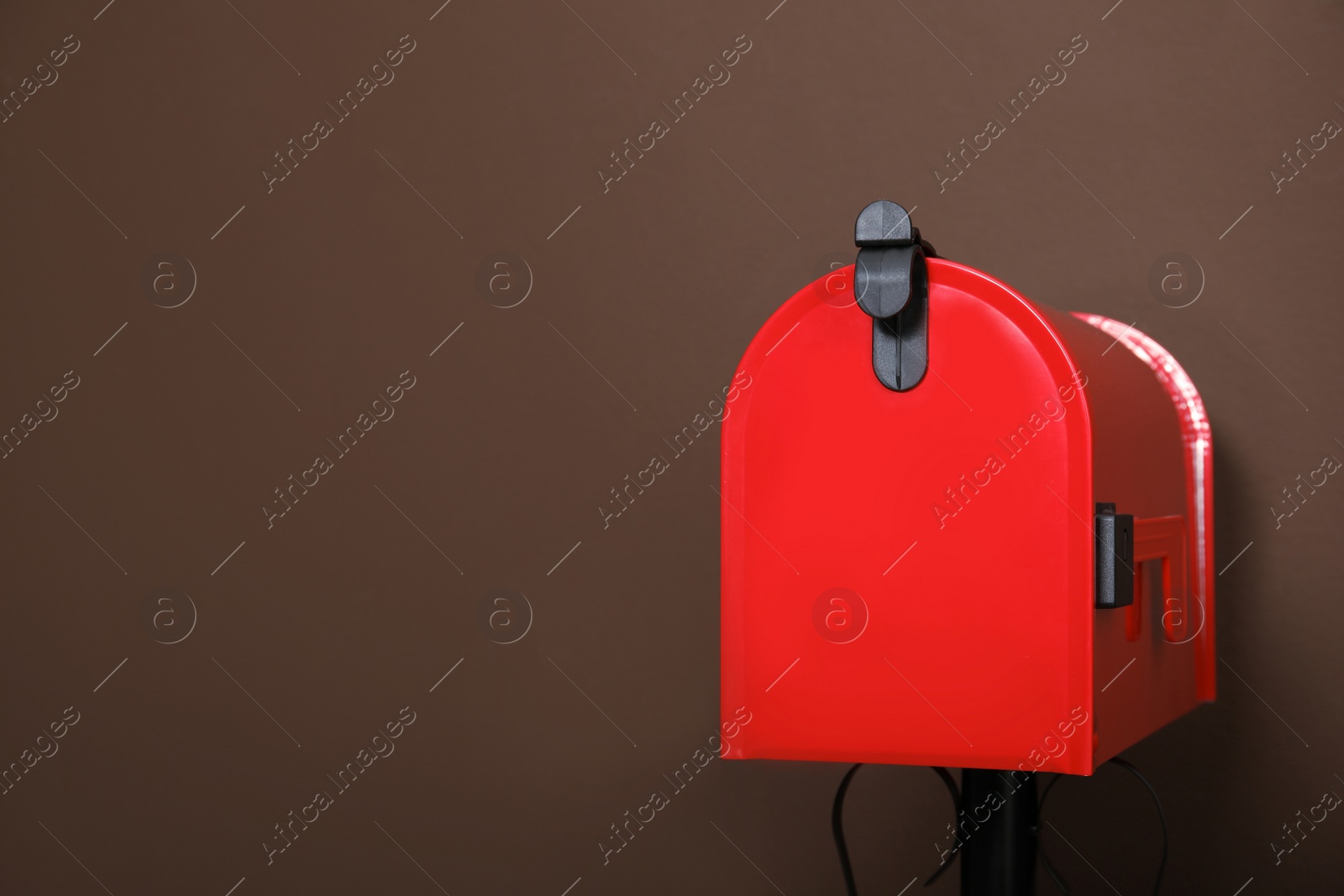 Photo of Closed red letter box against brown background. Space for text