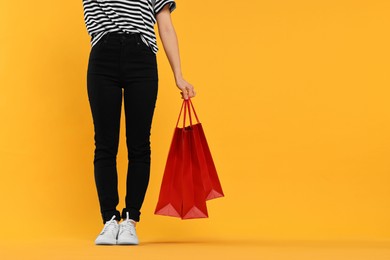 Photo of Woman with shopping bags on yellow background, closeup. Space for text