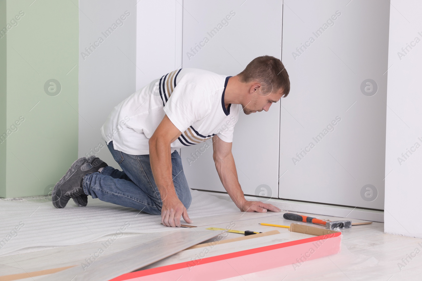 Photo of Man installing new laminate flooring in room