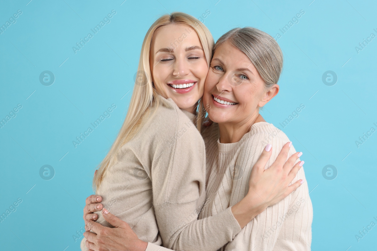 Photo of Family portrait of young woman and her mother on light blue background