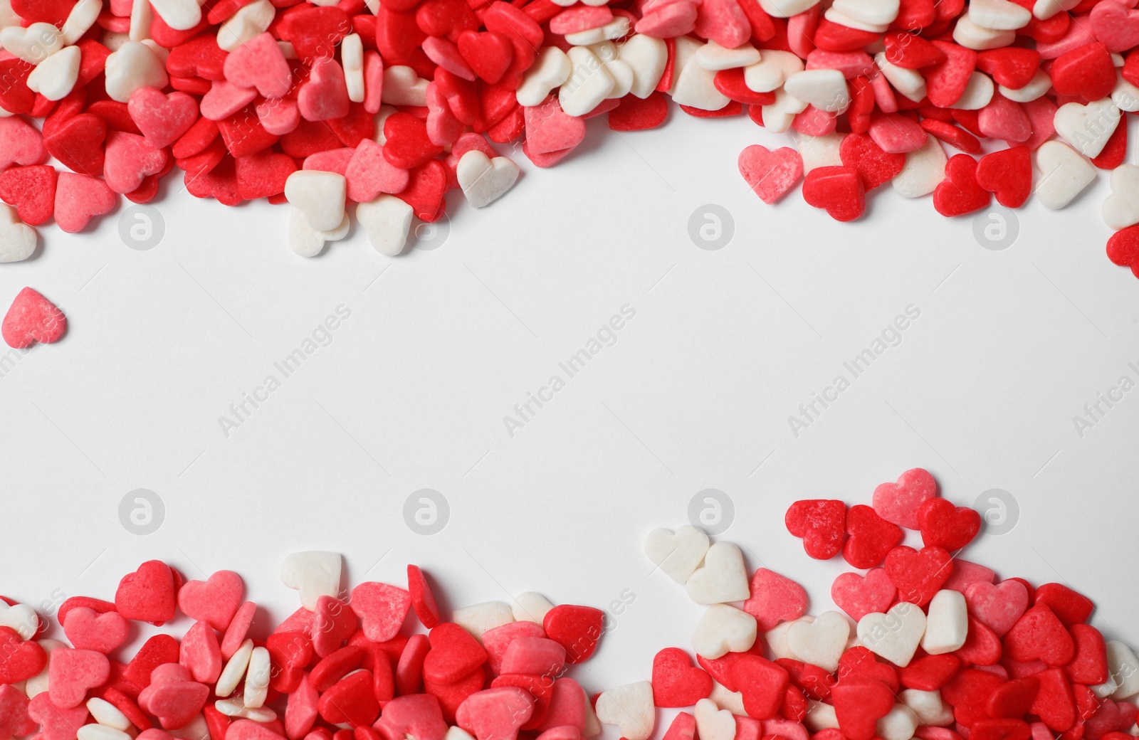 Photo of Bright heart shaped sprinkles on white background, view from above. Space for text