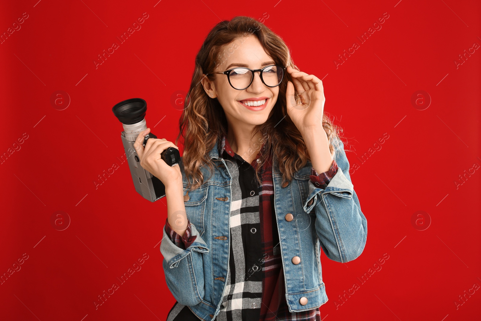 Photo of Beautiful young woman with vintage video camera on red background